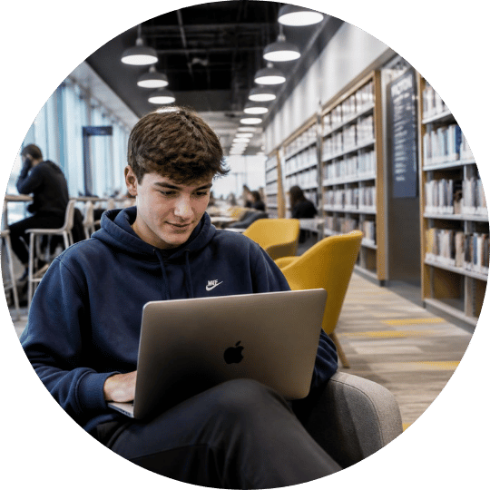 Estudiante utilizando su computador en una biblioteca